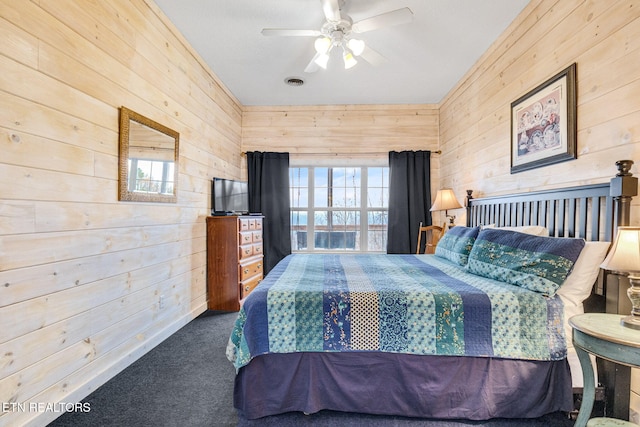 bedroom with carpet flooring, wood walls, and ceiling fan