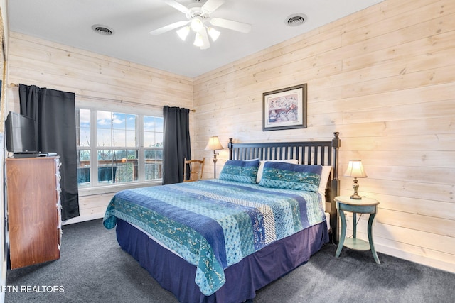 carpeted bedroom featuring ceiling fan and wood walls