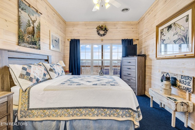 bedroom with carpet flooring, ceiling fan, and wooden walls