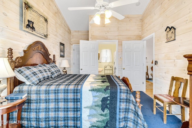 carpeted bedroom with vaulted ceiling, ceiling fan, and wood walls