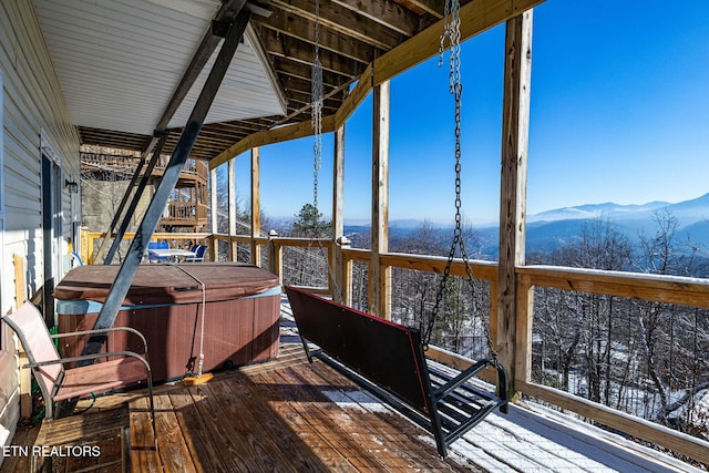 snow covered deck featuring a mountain view and a hot tub