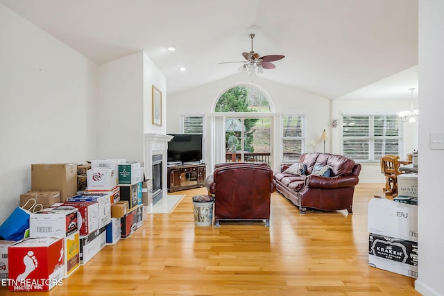 living room featuring hardwood / wood-style floors, ceiling fan with notable chandelier, and vaulted ceiling