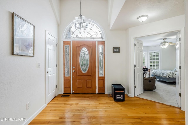 entrance foyer with ceiling fan with notable chandelier and light wood-type flooring