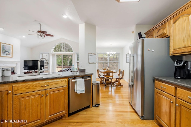 kitchen with pendant lighting, ceiling fan with notable chandelier, sink, light hardwood / wood-style flooring, and stainless steel appliances