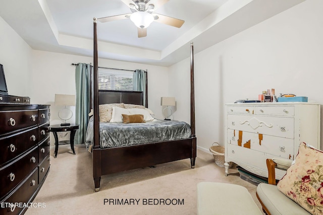 carpeted bedroom with ceiling fan and a raised ceiling