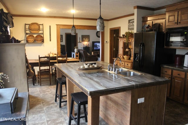 kitchen featuring a kitchen bar, crown molding, black appliances, sink, and pendant lighting