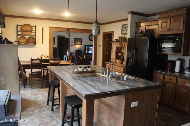 kitchen featuring a kitchen breakfast bar, a kitchen island with sink, sink, black appliances, and pendant lighting