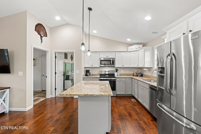 kitchen with appliances with stainless steel finishes, sink, decorative light fixtures, a kitchen island, and lofted ceiling