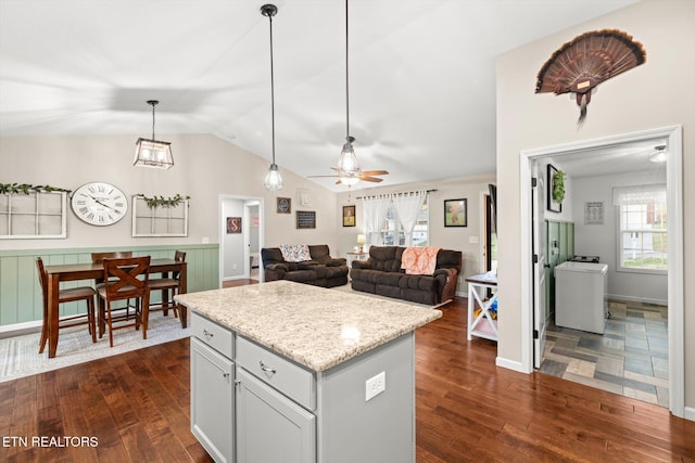 kitchen with a wealth of natural light, ceiling fan, dark wood-type flooring, decorative light fixtures, and a kitchen island