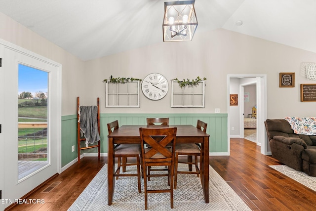 dining area featuring dark hardwood / wood-style floors, an inviting chandelier, and lofted ceiling