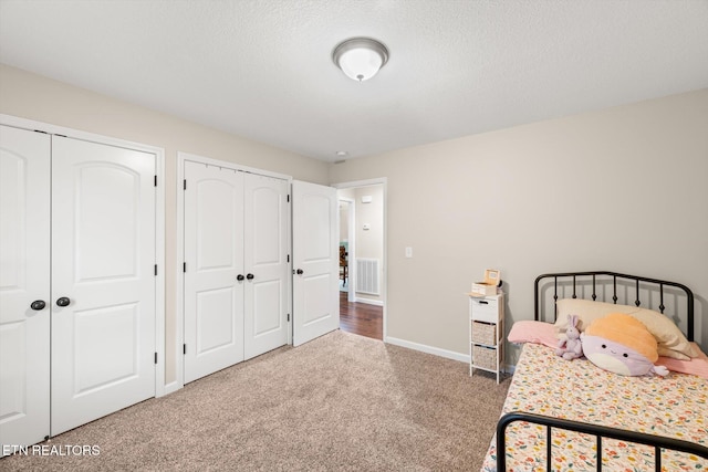 bedroom featuring multiple closets, carpet floors, and a textured ceiling