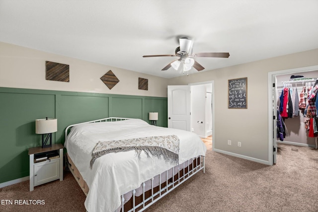 carpeted bedroom with a walk in closet, a closet, and ceiling fan