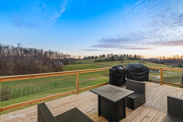 deck at dusk featuring a lawn, area for grilling, and an outdoor fire pit