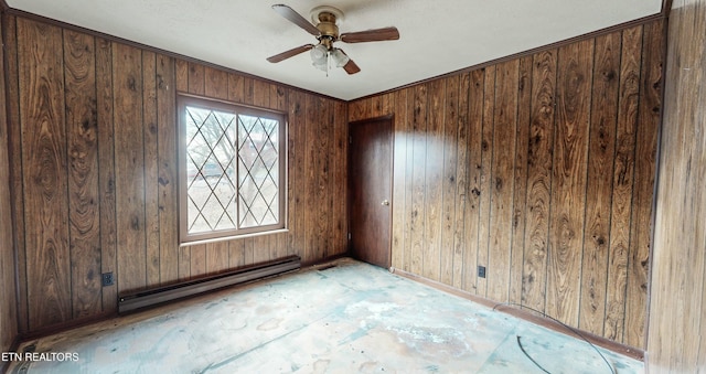 spare room featuring wooden walls, ceiling fan, and a baseboard heating unit