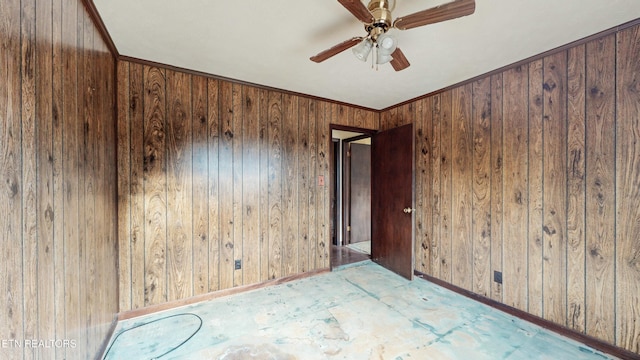 empty room featuring ceiling fan, wood walls, and crown molding