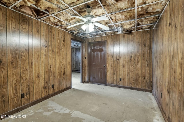 below grade area featuring wooden walls and a ceiling fan