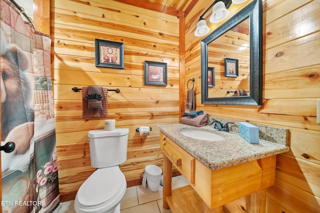 bathroom with wooden walls, tile patterned flooring, vanity, and toilet