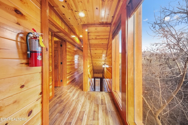 hall with hardwood / wood-style flooring, wood ceiling, and wooden walls