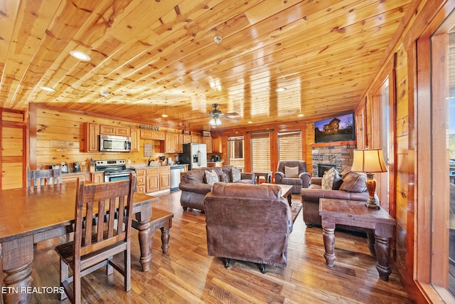 living room featuring light hardwood / wood-style floors, ceiling fan, wood walls, and wooden ceiling