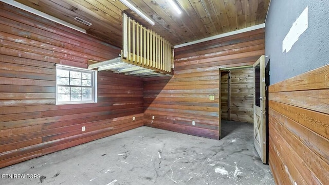 interior space featuring concrete flooring, wooden walls, and wood ceiling