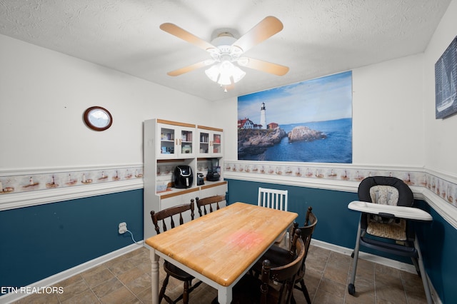 dining space with ceiling fan and a textured ceiling