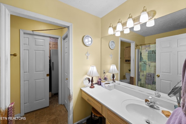 bathroom with walk in shower, tile patterned floors, a textured ceiling, toilet, and vanity