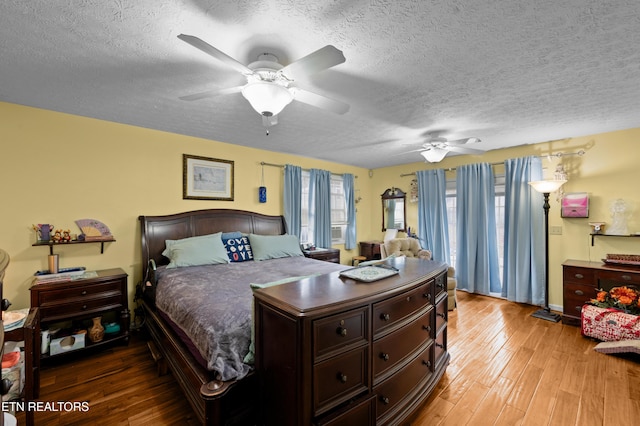 bedroom with hardwood / wood-style floors, ceiling fan, and a textured ceiling