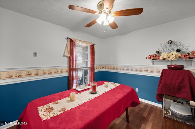 bedroom featuring ceiling fan, dark hardwood / wood-style flooring, and a textured ceiling