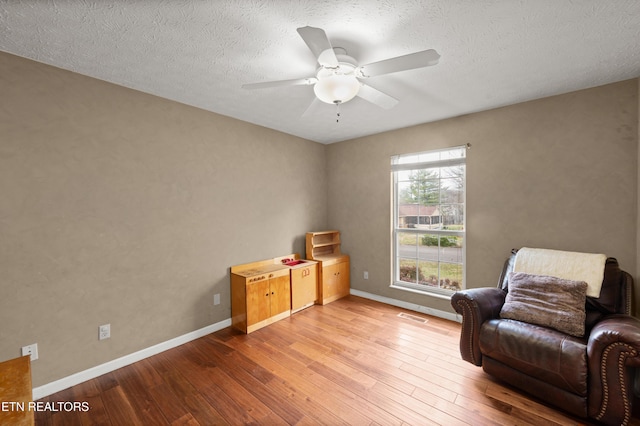 sitting room with a textured ceiling, light hardwood / wood-style flooring, and ceiling fan