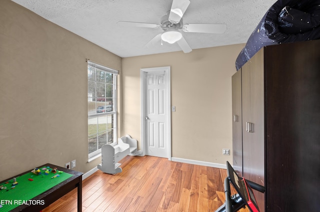 playroom with a textured ceiling, light hardwood / wood-style flooring, and plenty of natural light