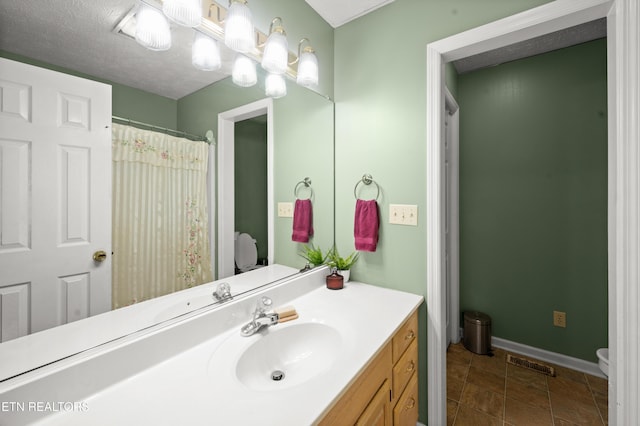 bathroom with vanity, a textured ceiling, and toilet