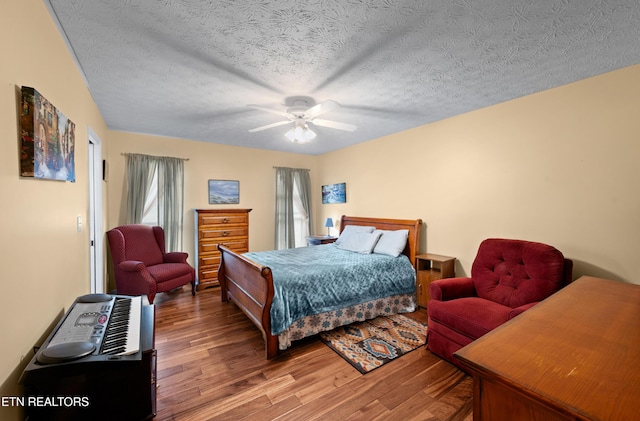 bedroom with ceiling fan, wood-type flooring, and a textured ceiling