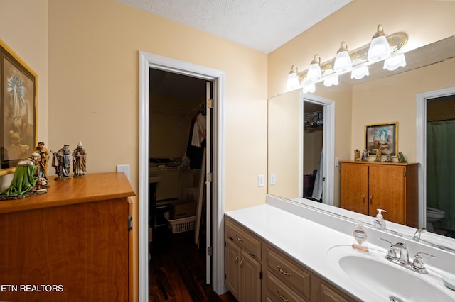 bathroom with hardwood / wood-style flooring, vanity, toilet, and a textured ceiling