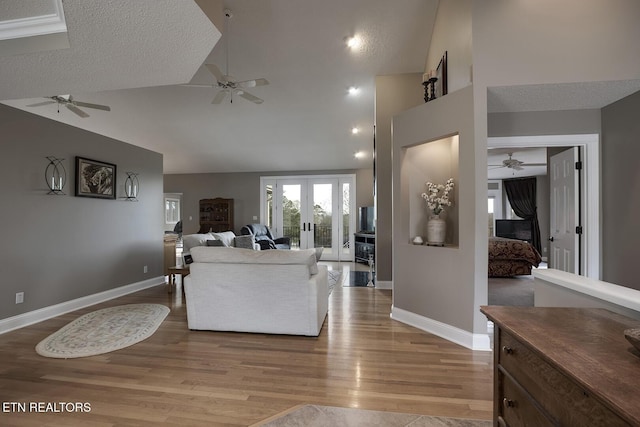 living room featuring hardwood / wood-style flooring, a textured ceiling, high vaulted ceiling, and french doors