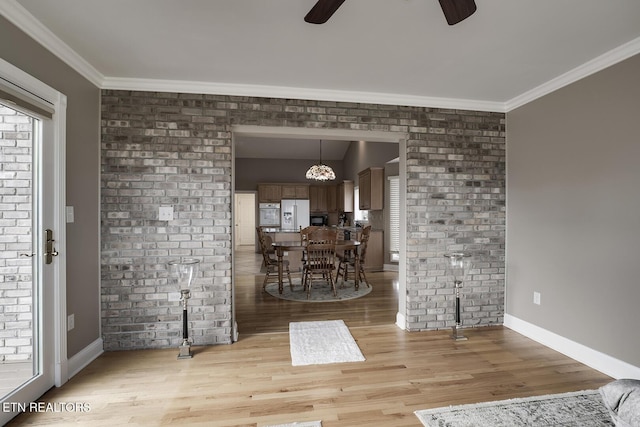 interior space featuring crown molding, ceiling fan, brick wall, and light wood-type flooring