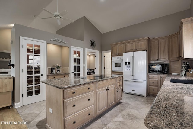 kitchen with a center island, sink, high vaulted ceiling, dark stone counters, and black appliances