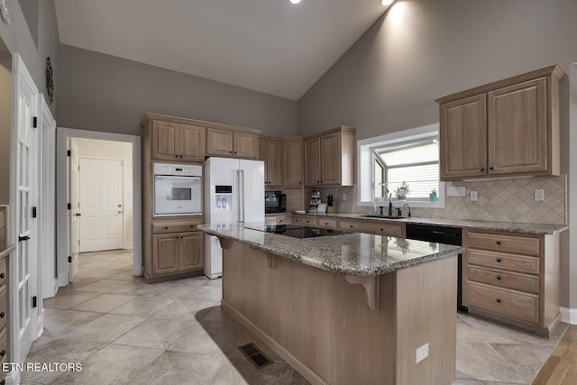 kitchen with stone counters, high vaulted ceiling, black appliances, a kitchen breakfast bar, and a kitchen island