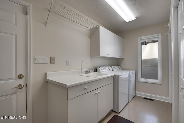 washroom featuring washer and clothes dryer, cabinets, a textured ceiling, and sink