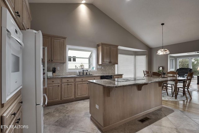 kitchen featuring a breakfast bar, a center island, high vaulted ceiling, black appliances, and sink