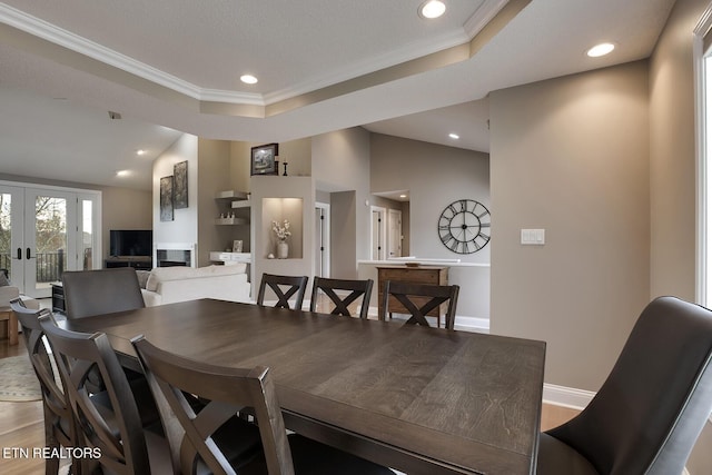 dining room featuring hardwood / wood-style floors, a tray ceiling, french doors, and crown molding