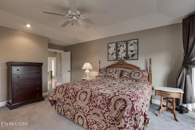 bedroom with a raised ceiling, ceiling fan, and light colored carpet