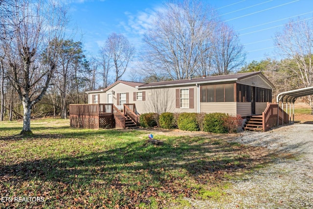 view of front of house with a carport, a sunroom, a deck, and a front yard