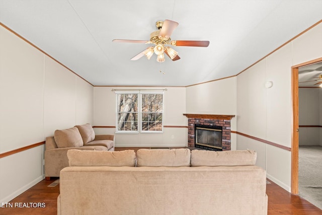 living room with ceiling fan, hardwood / wood-style floors, ornamental molding, and a brick fireplace