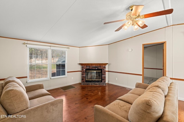 living room featuring ceiling fan, dark hardwood / wood-style flooring, crown molding, lofted ceiling, and a fireplace