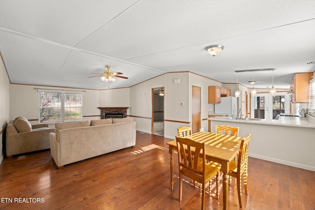 dining space with dark hardwood / wood-style floors, ceiling fan, crown molding, and a fireplace