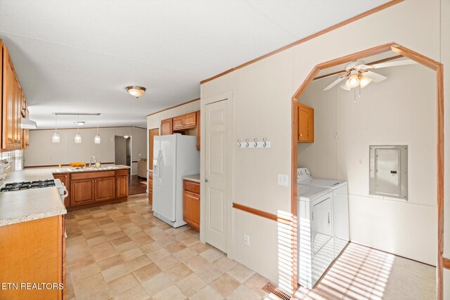 kitchen featuring white refrigerator with ice dispenser, electric panel, ceiling fan, decorative light fixtures, and washing machine and clothes dryer