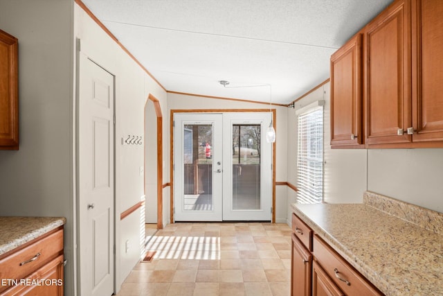 kitchen with a textured ceiling, french doors, vaulted ceiling, and ornamental molding