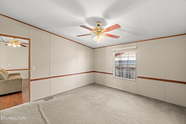 carpeted spare room with ceiling fan and crown molding