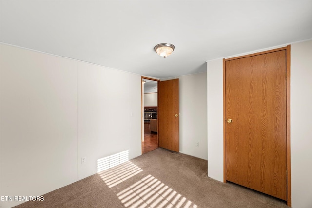 unfurnished bedroom featuring light carpet and a closet