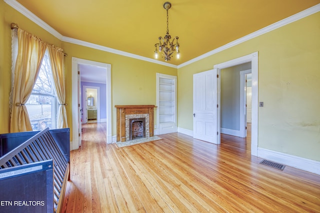 unfurnished living room featuring an inviting chandelier, wood-type flooring, and ornamental molding